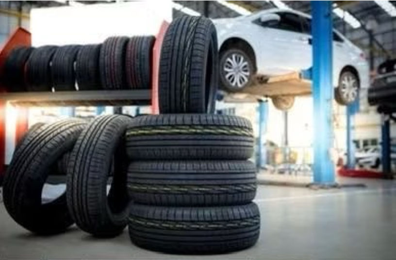 New tires stacked in the shop with a vehicle on the lift